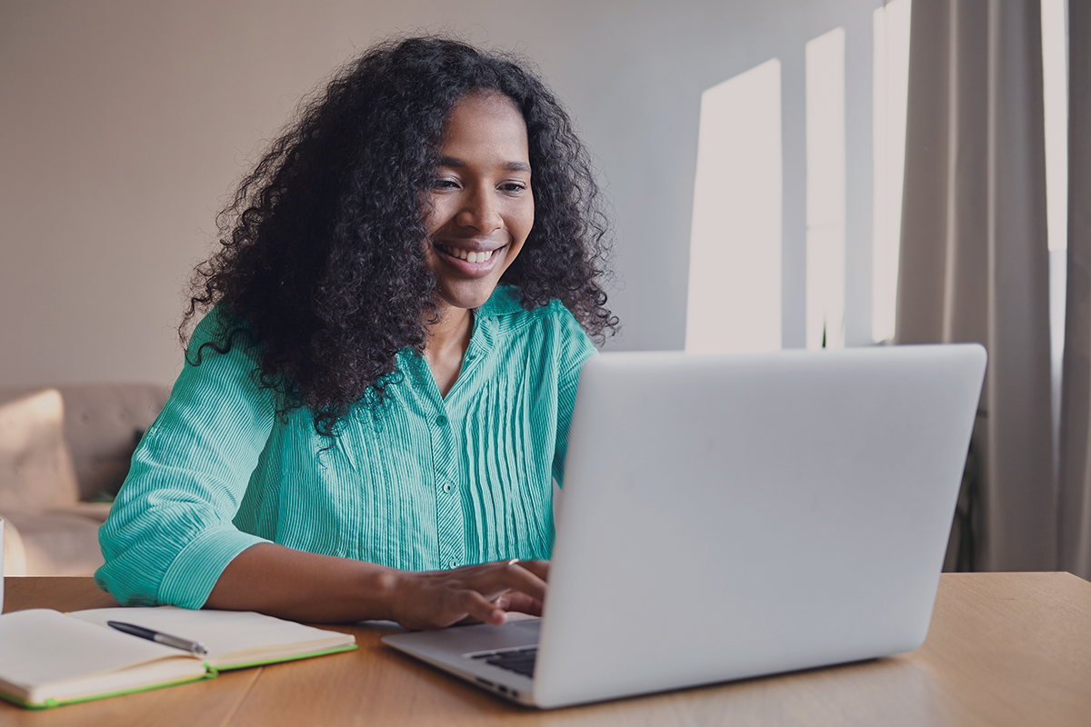 Jovem utilizando notebook em uma mesa de madeira