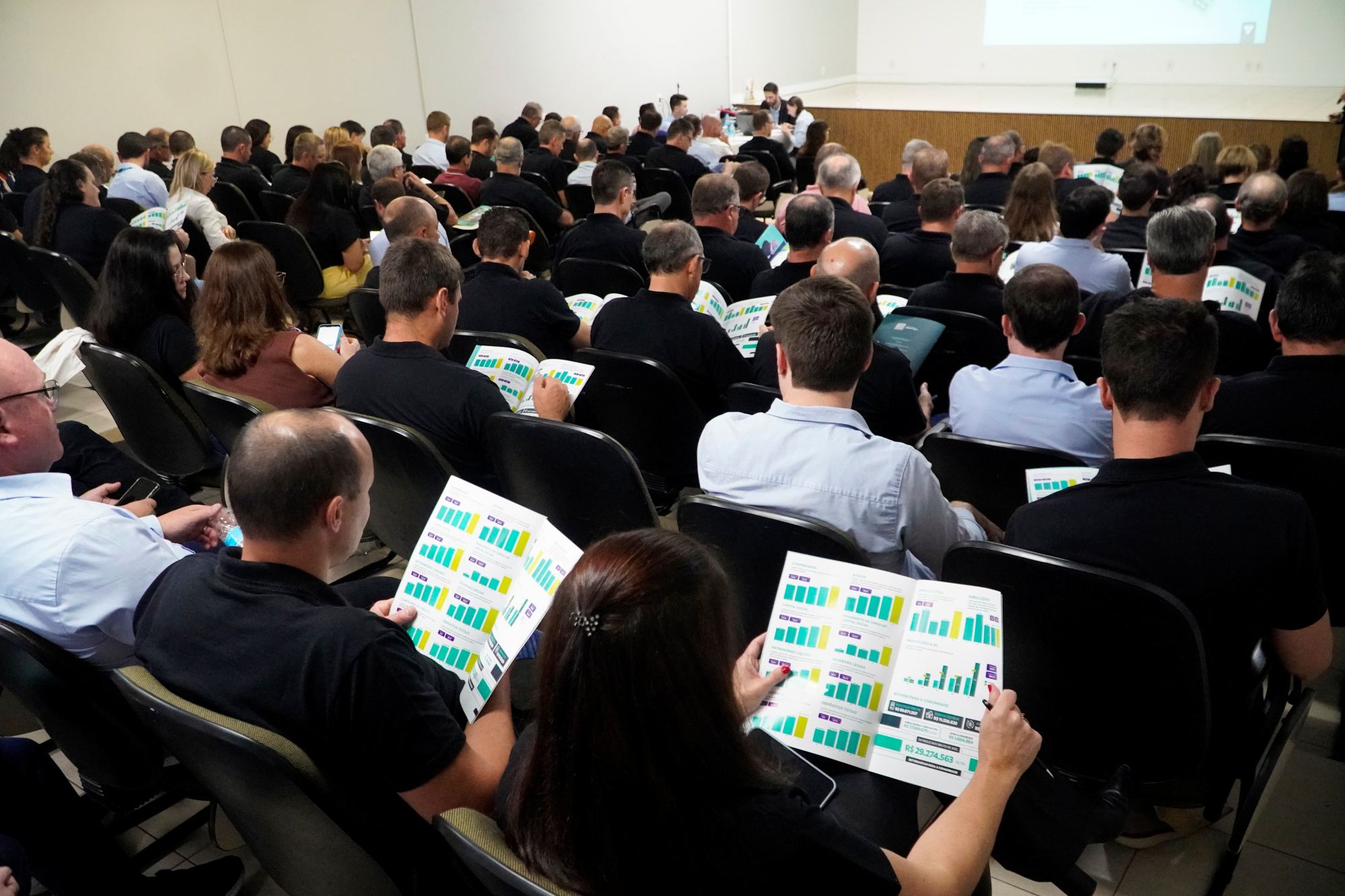 Pessoas com relatorio em maos para acompanhar a Assembleia