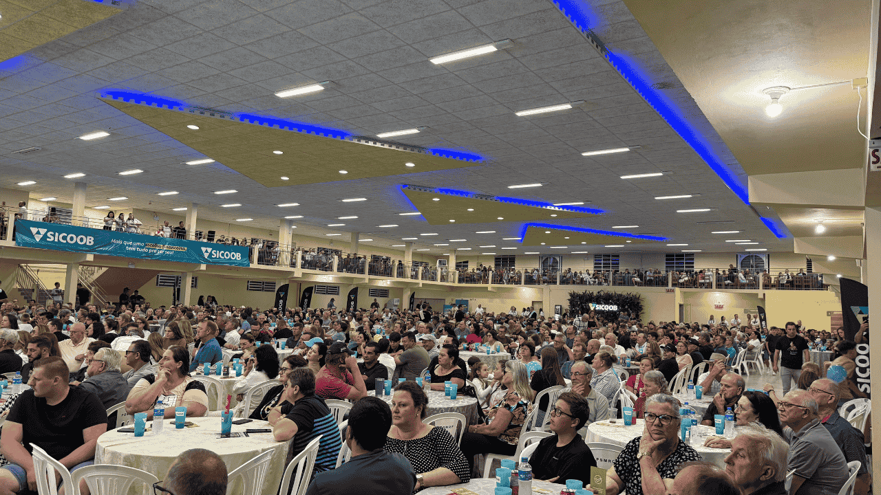 Salão amplo com muitas pessoas participando de uma reunião.