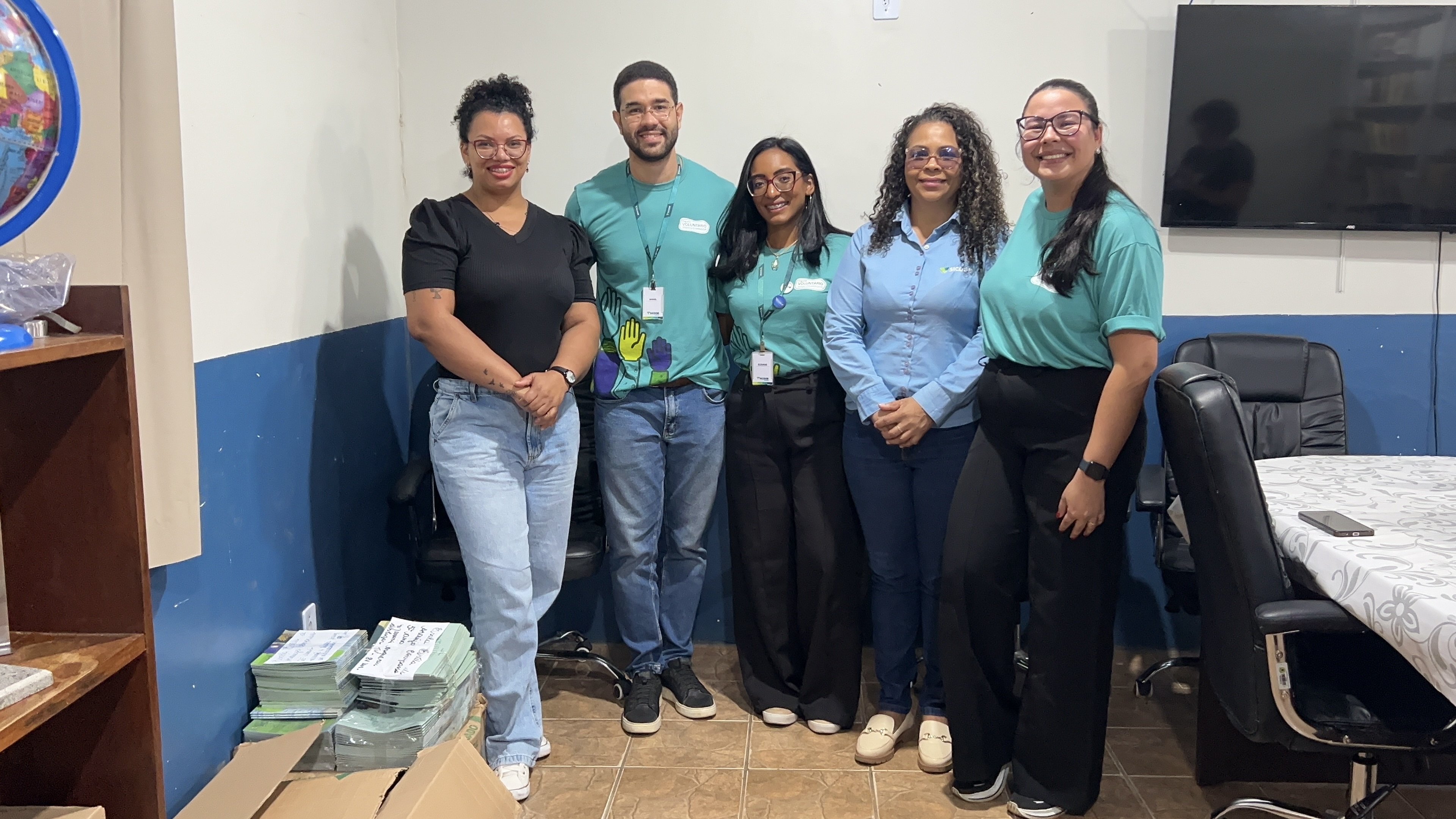 Equipe Sicoob Credjurd entregando livros da Coleção Financinhas