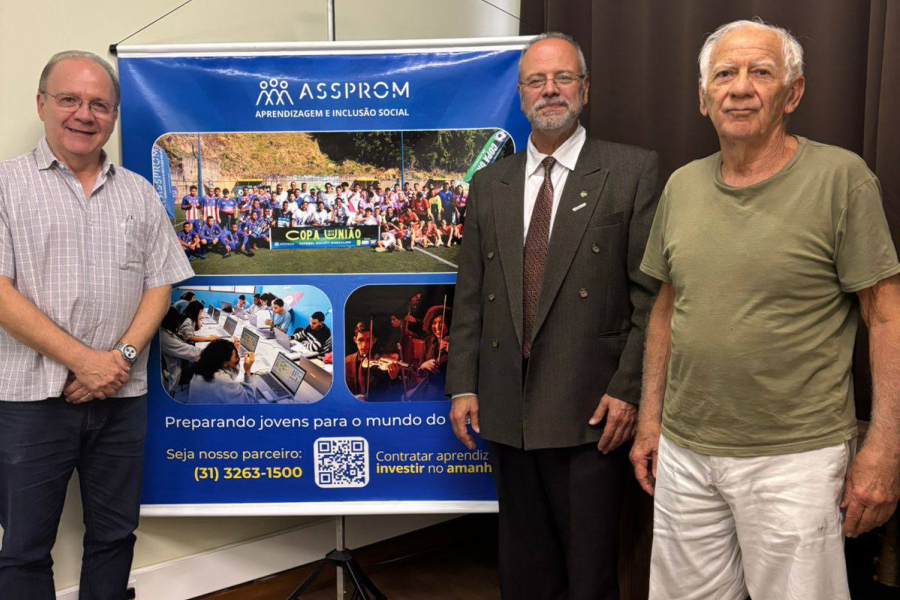 Três representantes institucionais durante encontro ao lado de painel da ASSPROM, destacando iniciativas voltadas à aprendizagem e inclusão social de jovens.